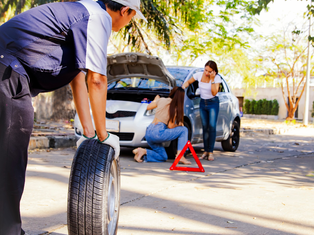 Young man changing tire to help his girlfriend with broken car on the road